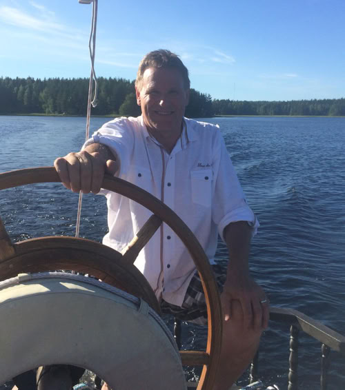 Wine tasting table setup with various bottles, glasses, and a sommelier in a refined indoor setting.