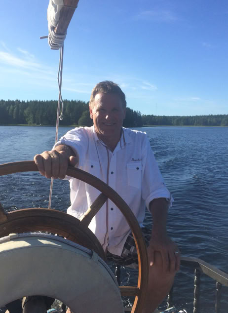 Wine tasting table setup with various bottles, glasses, and a sommelier in a refined indoor setting.